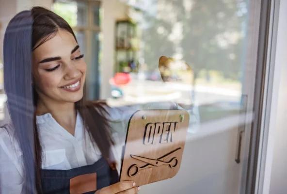 Salon owner hanging up the "open" sign